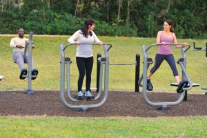 Image of people using outdoor fitness equipment installed on a rubber trail surface